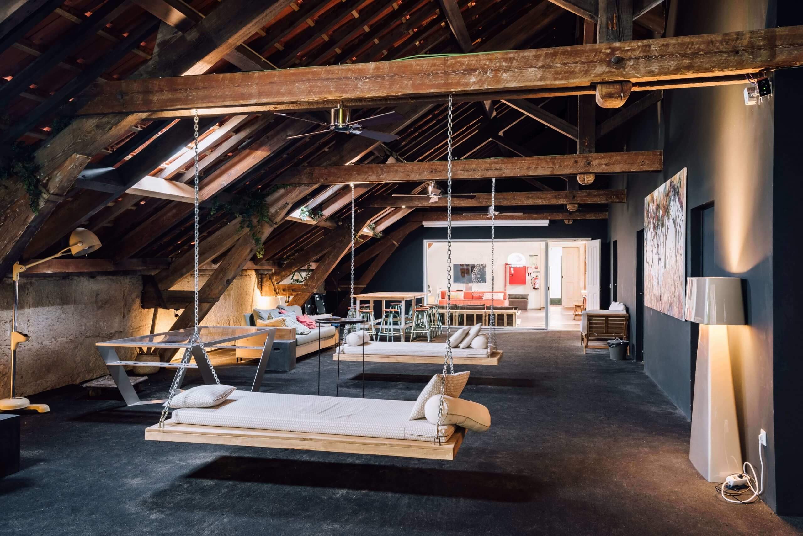 Attic lounge with hanging beds under wooden beams