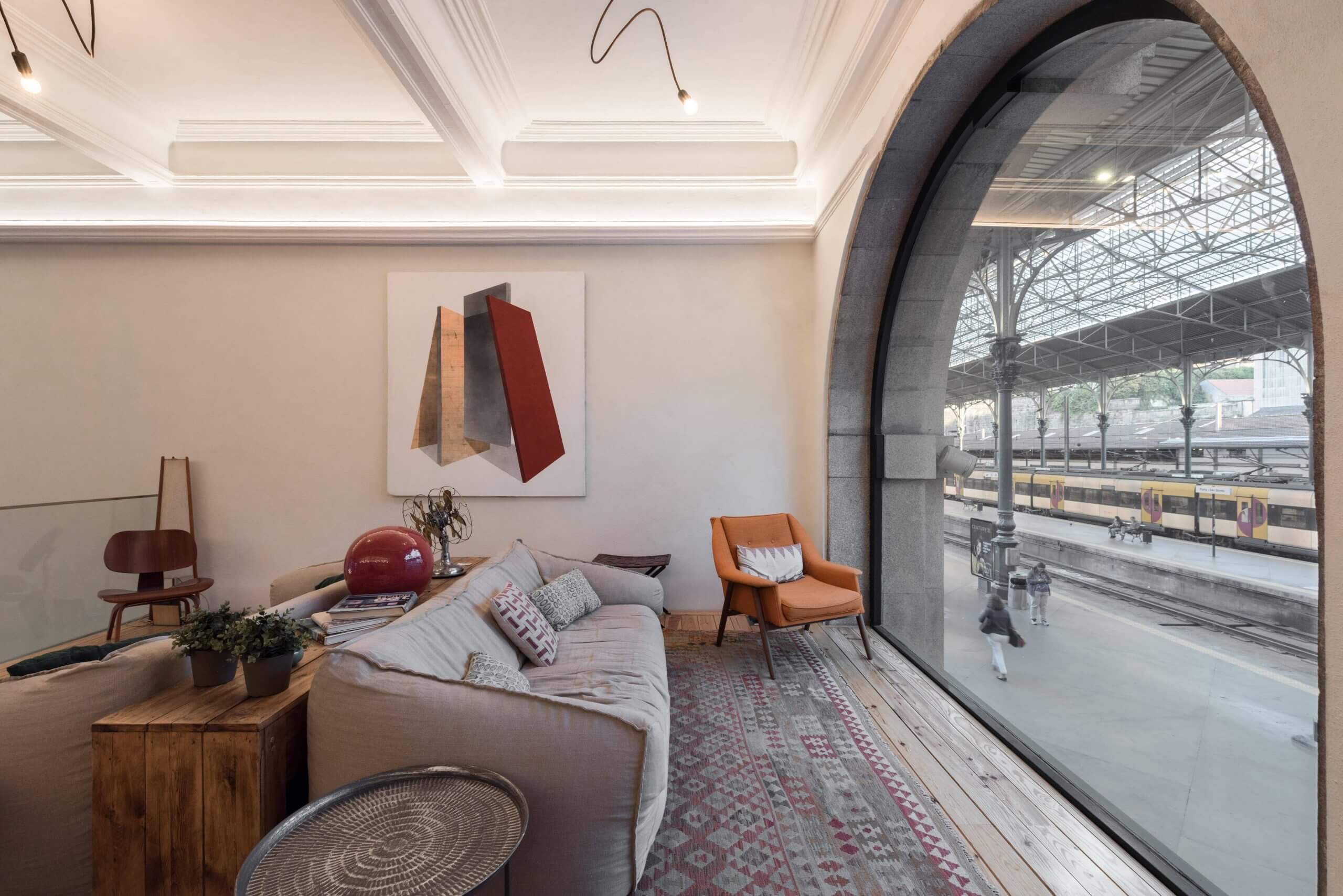The lounge at The Passenger, with a tall arched window looking onto the São Bento platforms